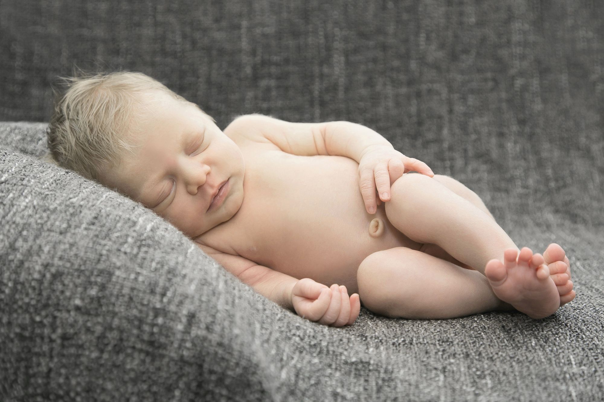 Neugeborenenfotografie zu Hause auf grauer Decke